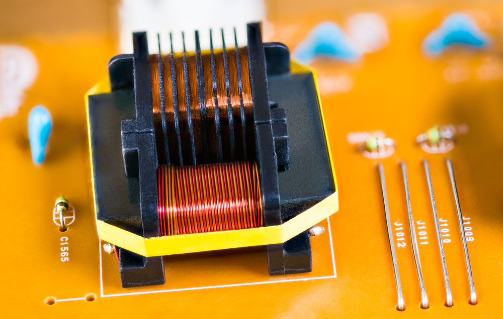 Magnetic ferrite core transformer detail on beige printed circuit board
